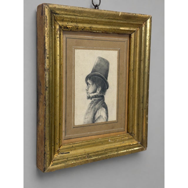 This finely rendered profile portrait portrays a fashionable gentleman facing left and wearing an exceptionally tall top...