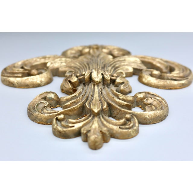 A substantial gilt scroll and fleur-de-lis wall piece, cast in resin with the deep relief and layered acanthus detail of a...