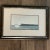 Unsigned art, presumed to be print, framed under glass. Scene depicts a dory-type boat on a choppy lake. Colors are subtle...