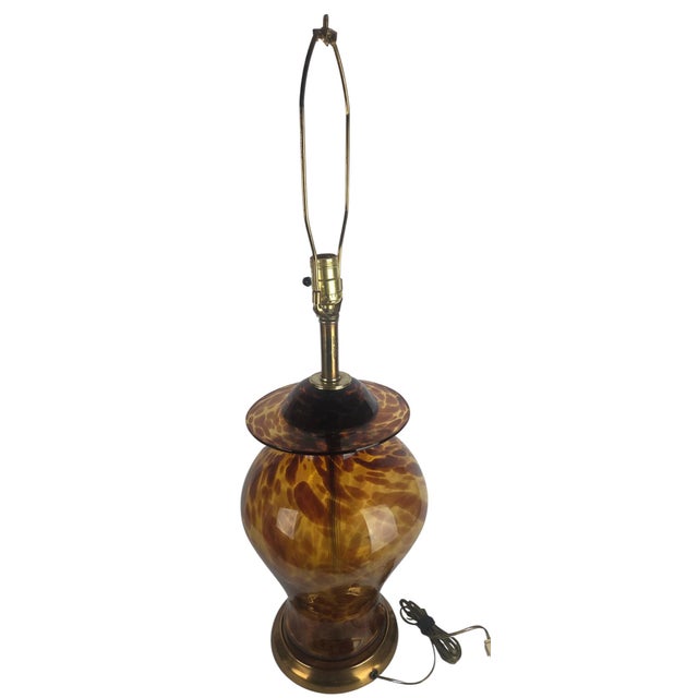 A vintage table lamp in amber tortoiseshell pattern art glass, featuring a baluster body and flared glass collar beneath...