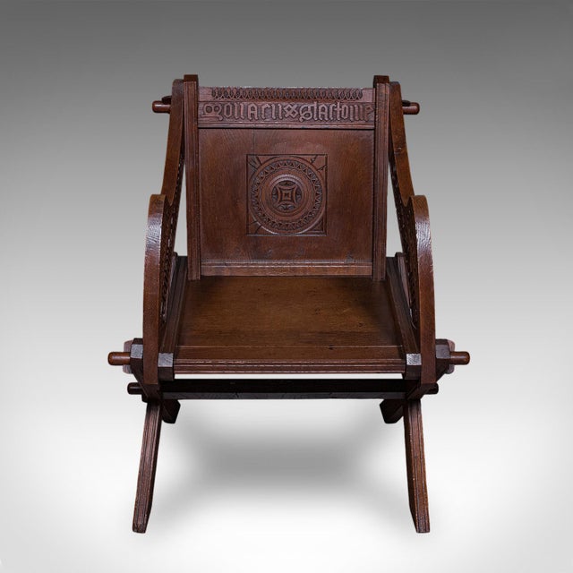 This is an antique inscribed Glastonbury chair. An English, oak armchair in Gothic Revival taste, dating to the late...
