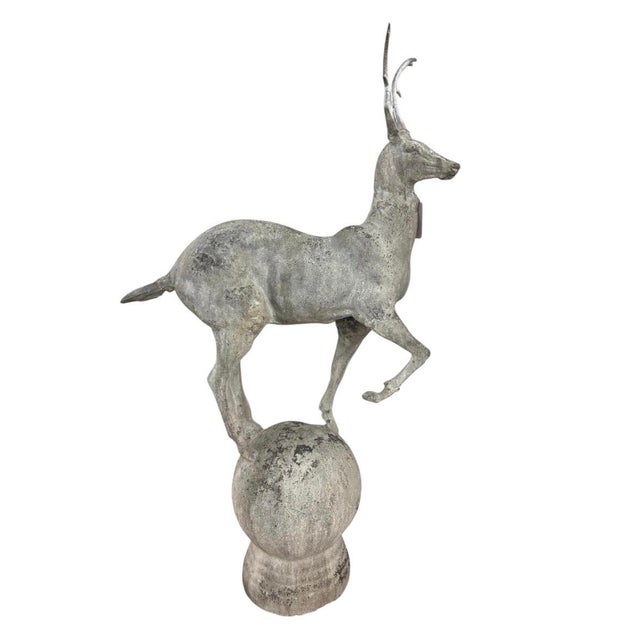 This striking vintage cast iron statue features a stylized gazelle posed dynamically atop a large spherical orb mount....