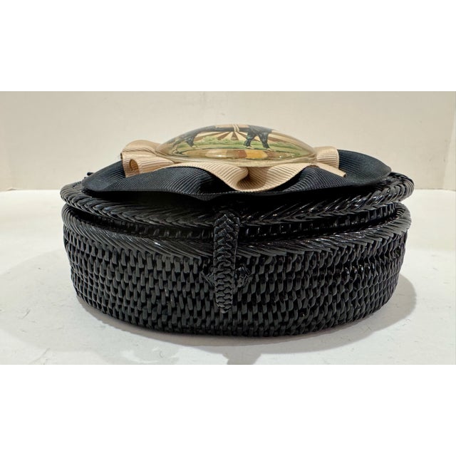 Vintage round covered decorative box with black woven body, pleated ribbon trim, and a horse image medallion at the center...