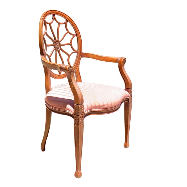 A refined vintage Hepplewhite-style armchair featuring the iconic spider web oval back, warm wood frame, and intricately...