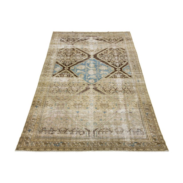 Hand-knotted wool antique Malayer rug featuring an all-over design with blue and beige accents on a brown color field....