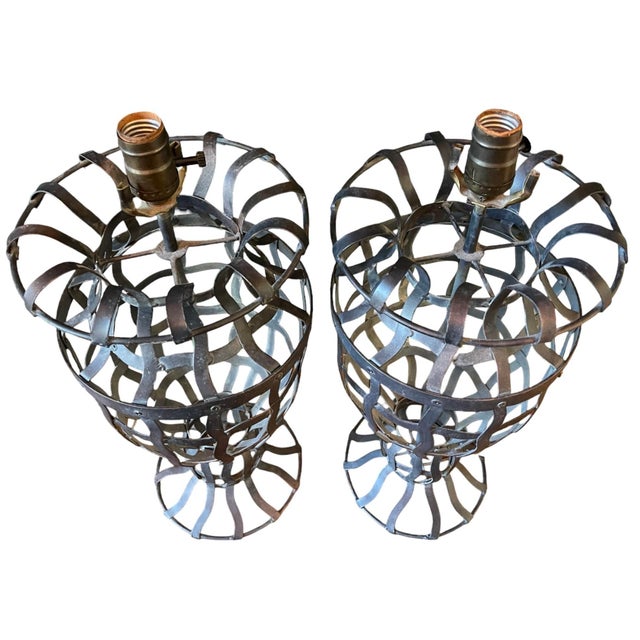 Striking pair of sculptural wrought iron table lamps in an open basket form. The hand-forged iron construction features...