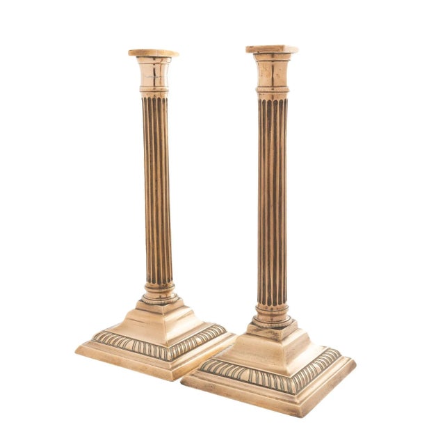 Pair of fluted columnar bell metal candlesticks on square stepped base with a gadroon molding. The hollow core cast candle...