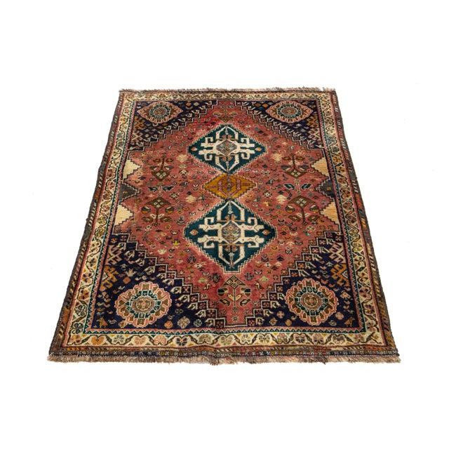 This vintage Shiraz wool rug features a red field with multicolored accents in the design. This rug measures 3'6'' x 5'2''.