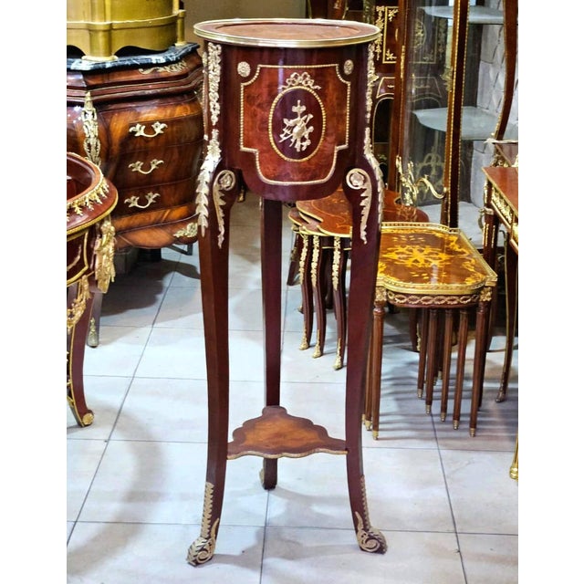This petite French-style side table features a rich wood finish complemented by delicate gold leaf ornamentation. Its...