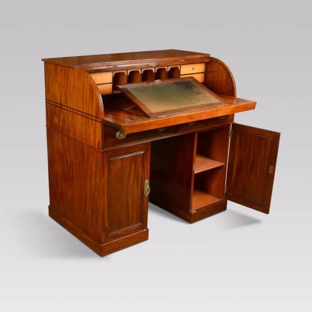 Mahogany twin pedestal roll top desk, the solid mahogany ebony strung roll front enclosing an arrangement of pigeon holes...