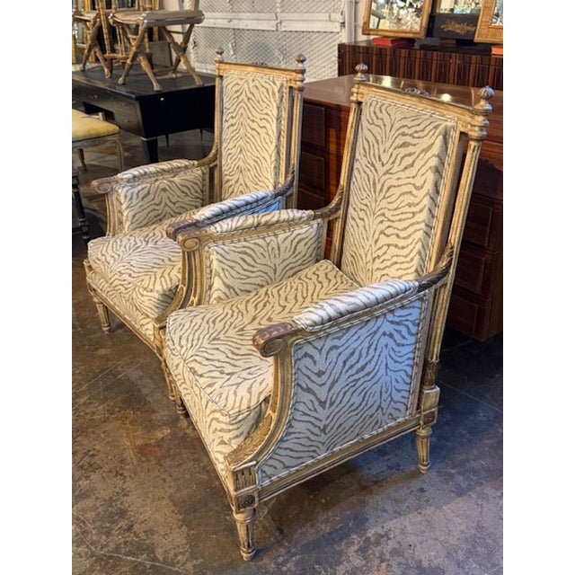 The product is a pair of antique French Louis XVI upholstered armchairs. These stylish armchairs feature intricate designs...