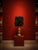 One-of-a-kind table lamp featuring an ornate antique gold-tone base with a dramatic black sculptural textured shade. The...