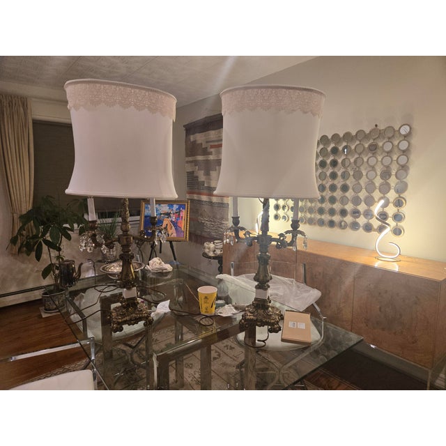 .A dramatic pair of 34-inch Mid‑Century Hollywood Regency table lamps featuring ornate cast metal scrollwork, crystal...