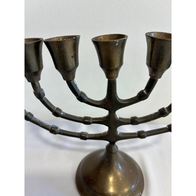 A vintage solid brass seven-branch menorah featuring elegant bamboo-inspired detailing and a warm aged patina. The...