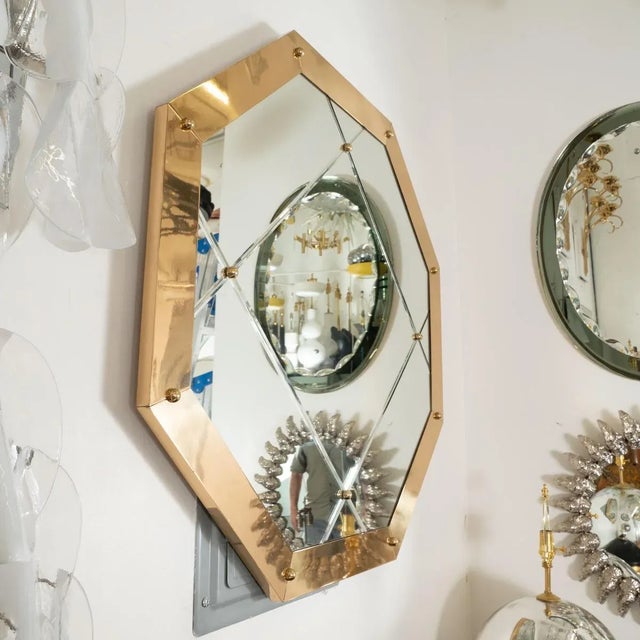 Octagonal brass mirror with beveled glass and ball finial details in the style of Karl Springer.