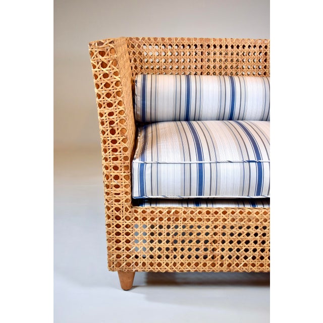 A double cane solid teak settee with newly upholstered seat & back bolster cushions in blue and white stripe Sunbrella...