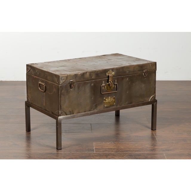 An English metal trunk from the early 20th century, on custom stand. Created in England during the first quarter of the...