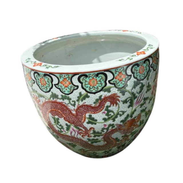 A vintage pair of Chinese export porcelain jardinieres with a dragon motif circling each planter. Coral and pink dragon is...