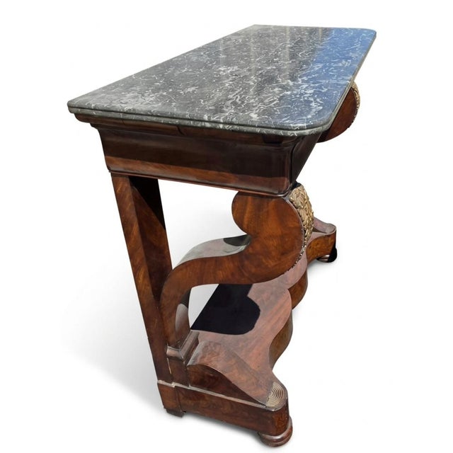 This piece of furniture is a French Second Empire / Charles X period mahogany console table featuring a variegated gray...
