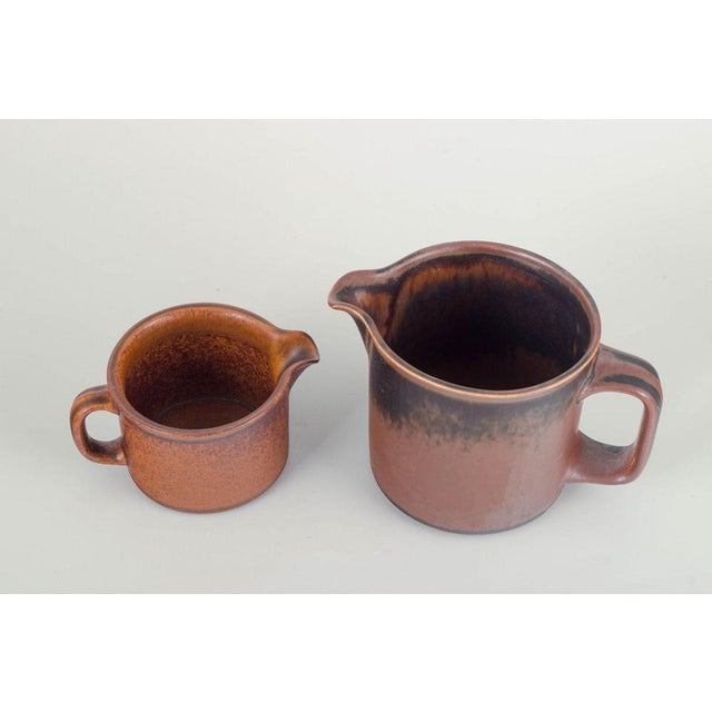 Ulla Procopé for Arabia Finland Two stoneware pitchers, 1970s. Cylindrical form with integrated handle and pouring spout,...
