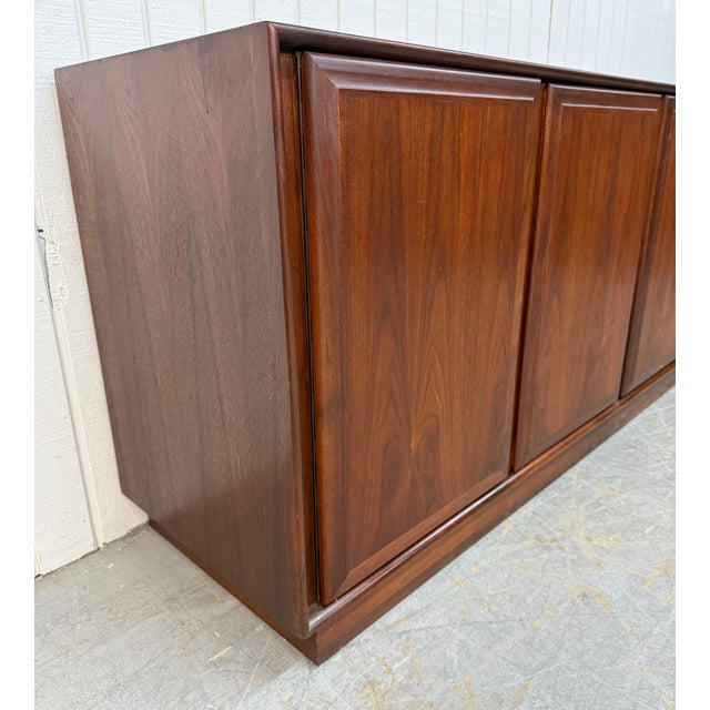 This striking Mid-Century Modern walnut four-door sideboard by Dillingham is a timeless blend of clean lines, rich wood...