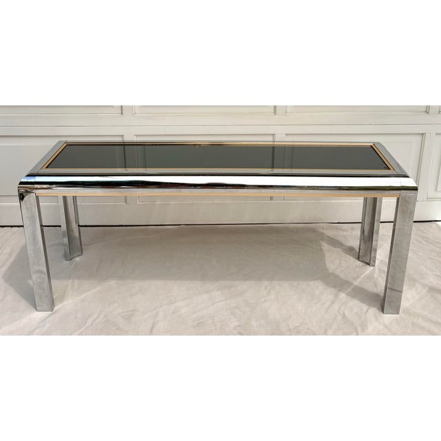 Here is a wonderful, modern/postmodern Parsons style console/sofa table in chrome and brass with a smoky mirrored top. The...