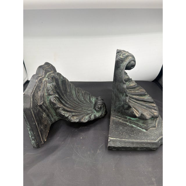 A very solid pair of wall brackets made out of plaster and painted dark gray to black with green highlights