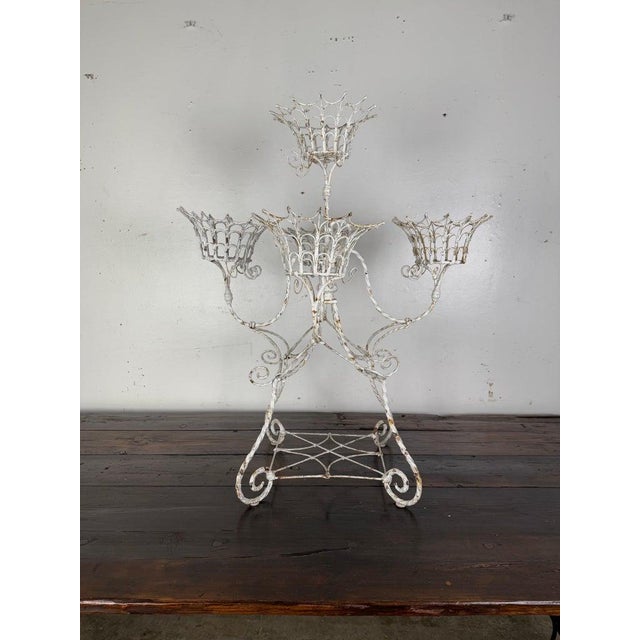 Vintage wrought iron metal planter with an ornate, decorative design. It features basket-like holders arranged...