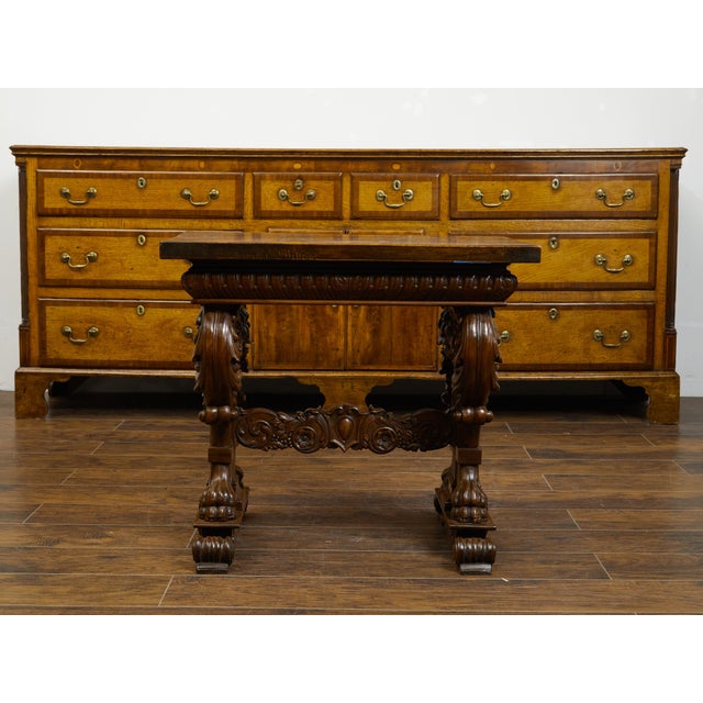 An Italian walnut small side table from the early 19th century, with lions' heads and richly carved trestle base. Created...