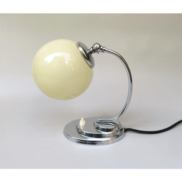 An elegant bedside lamp from the Art Deco Machine Age period, in a stylish combination of silver and beige, made in...