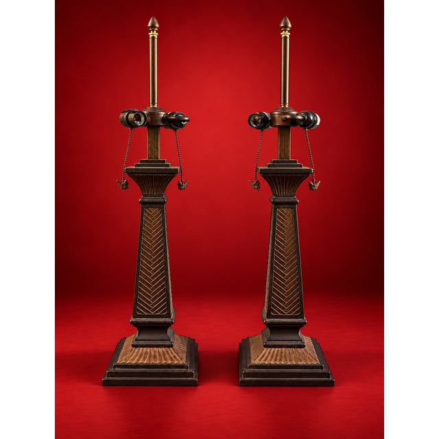 A striking pair of neoclassical-inspired table lamps featuring tall, sculptural architectural columns with richly detailed...