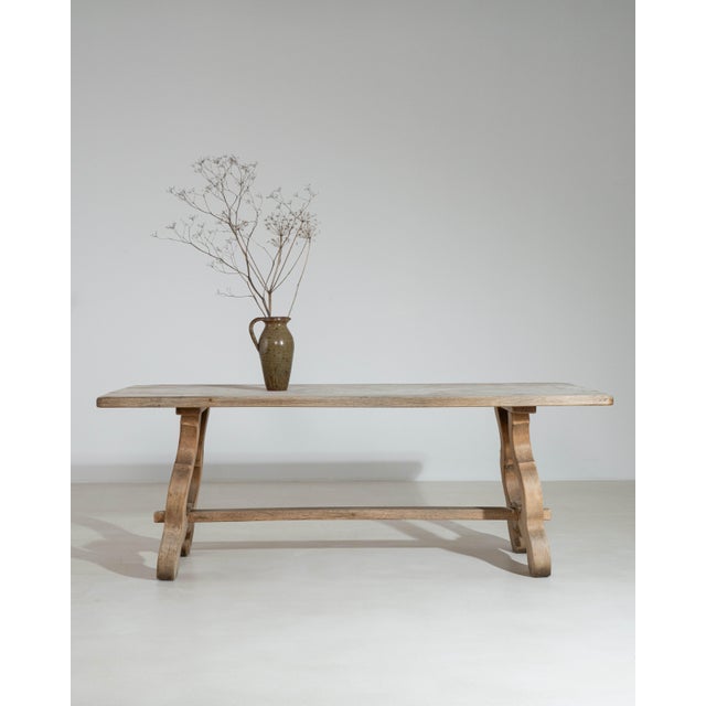 A distinctive French dining table featuring a harp-style base, showcasing curved wooden supports that add sculptural...
