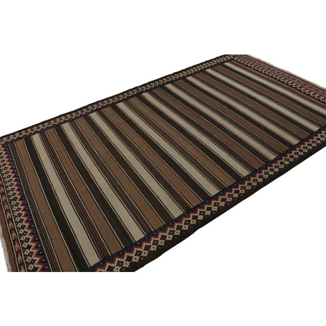 Handwoven in wool, circa 1950-1960, this 6x10 vintage Afghan tribal kilim, in beige/brown, features fencepost geometric...