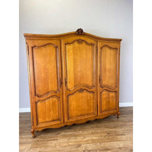 A beautifully presented Vintage French Louis wardrobe in oak, featuring three panelled doors, a graceful shaped top and...