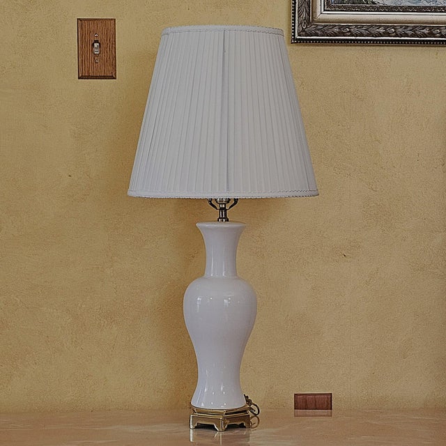 Vintage Paul Hanson table lamp featuring a glossy white porcelain baluster-form body raised on an elegant brass-tone...