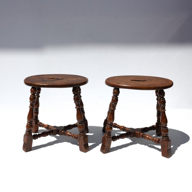 A pair of late-19th-century oval oak stools with shaped hand-grip apertures to the seats. Each stool is supported on four...