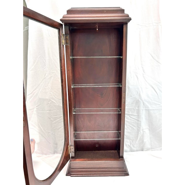 An antique oak tabletop curio cabinet with a glass door, removable glass shelves, and a tall narrow profile for displaying...