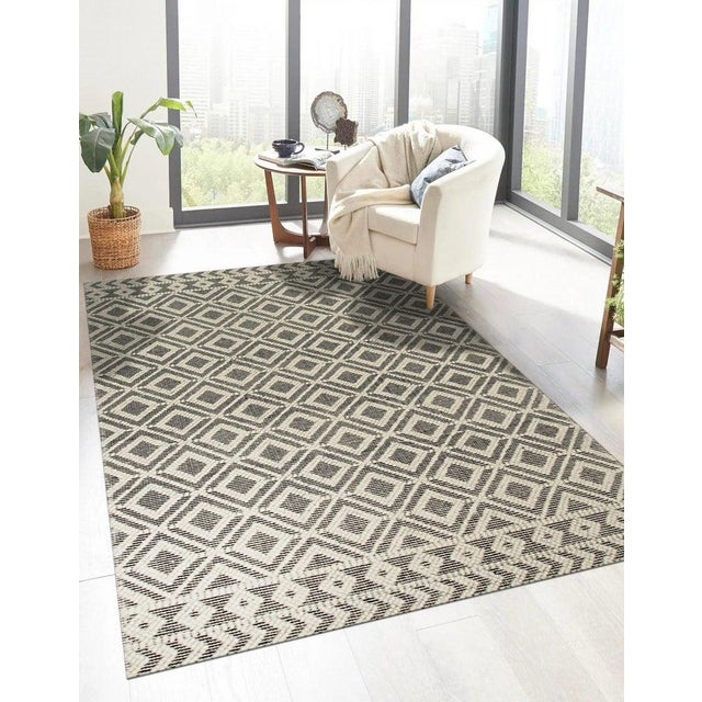 This black wool rug is defined by its hand knotted pile weave type. It incorporates a Kilim style aesthetic into a durable...