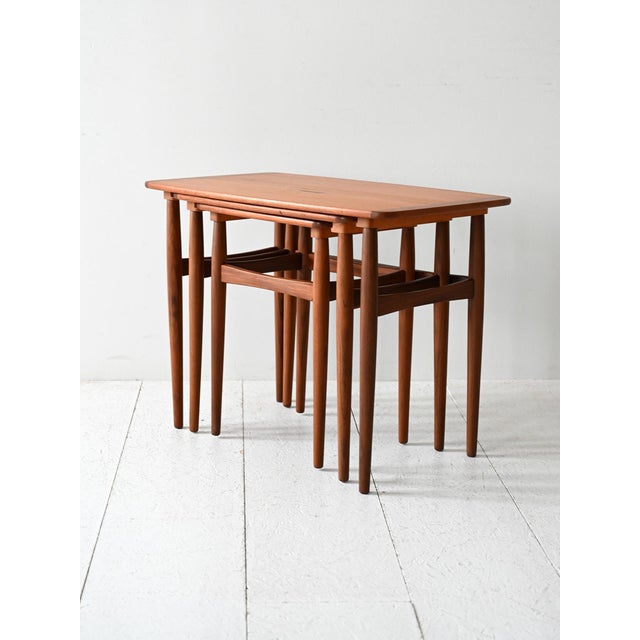 Three nesting teak tables from the 1960s with tapered turned legs and slightly contrasting finishes. Set of three...