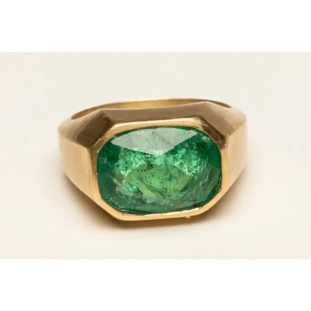 A stunning emerald-cut, faceted 5 carat emerald set in a beveled 18K gold band. Ring size is a 7. Classic and elegant. The...