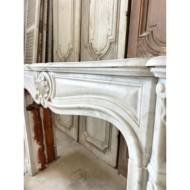 Large louis xv style fireplace in carrara white marble, late 19th century. Its lintel is decorated with a shell motif...