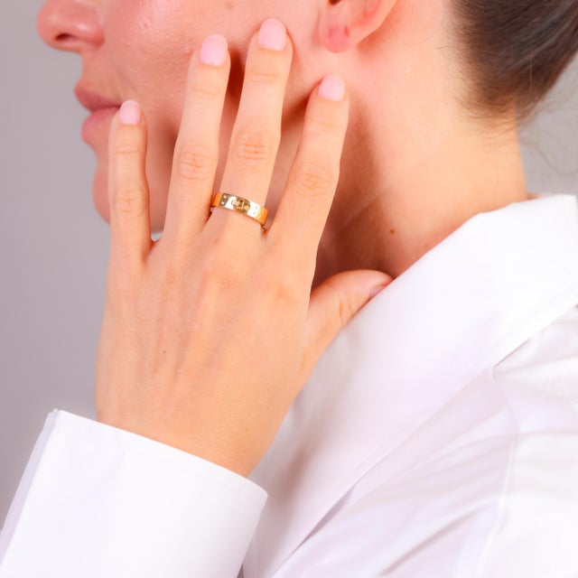 This modern Hermès ring, crafted in luxurious 18k yellow gold, features four sparkling diamonds, embodying understated...