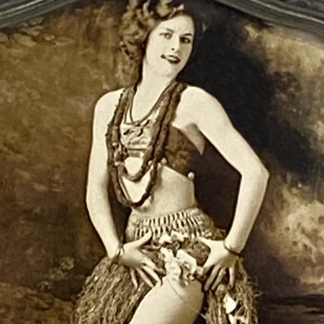 This striking and evocative antique sepia tone photograph, features a posed female hula dancer in traditional costume with...