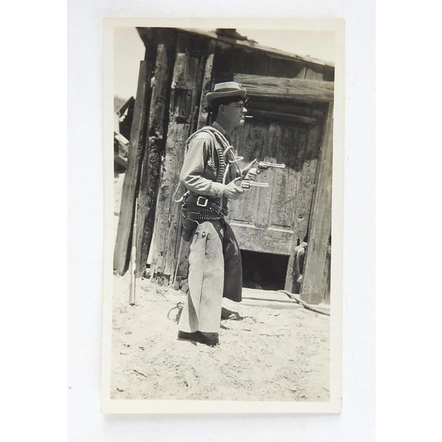 Circa 1940's sepia tone snapshot photograph of a man dressed up as a wild west outlaw or sheriff. To small pork pie hat,...
