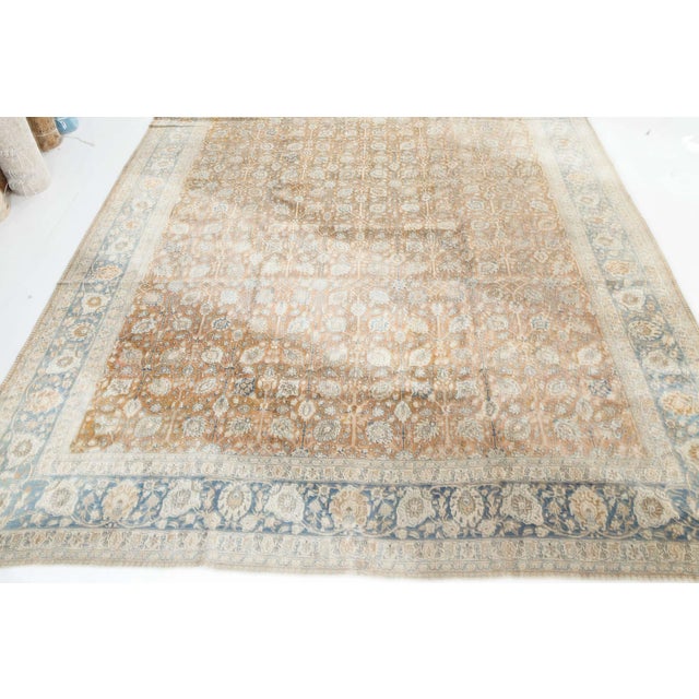An early 20th century Persian Tabriz antique rug, the light brown field with a miniature palmette and flowering vinery...