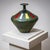 Ceramic vase with green glaze, black stripe decoration, and vertical rectangular accents in red, white, and yellow. The...