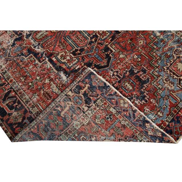 Beautiful antique Heriz hand-knotted wool rug with a red field. This Heriz rug has a dark blue frame and multi-color...