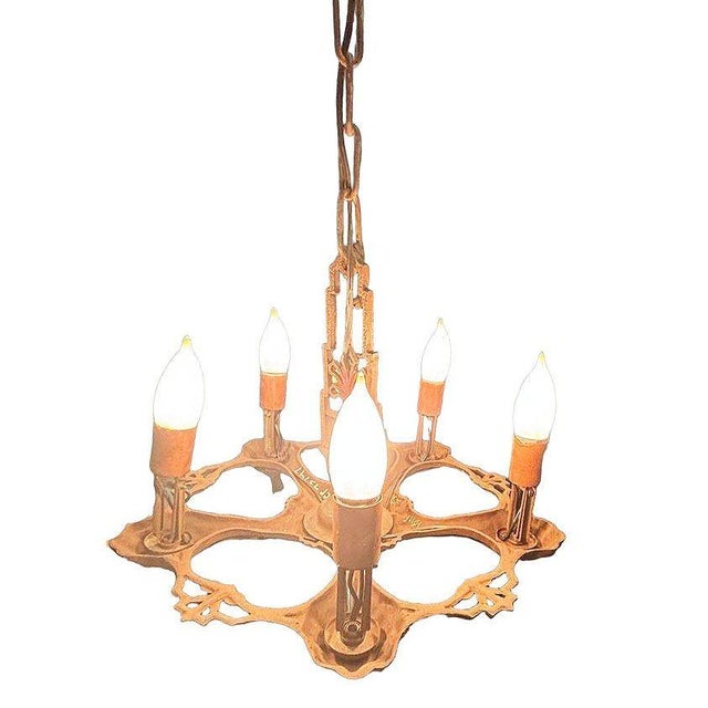 This Art Deco chandelier features a sculptural brass frame with a warm copper-toned finish. Five arms extend from the...
