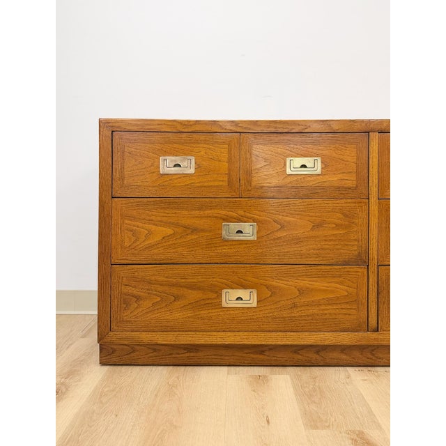 This vintage lowboy dresser by Dixie showcases the clean, tailored silhouette of classic campaign-style design, finished...