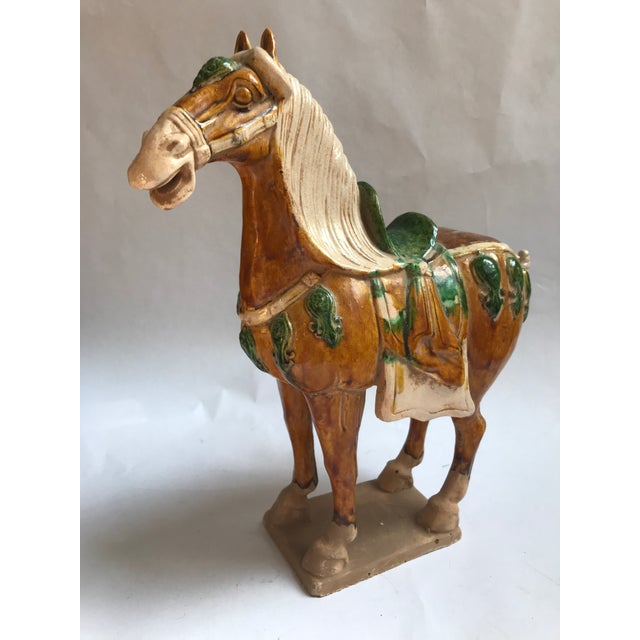 A striking mid-20th century Chinese ceramic horse modeled after the celebrated sancai-glazed horses of the Tang Dynasty....